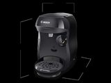 La machine à café est noire et intègre une cafetière.