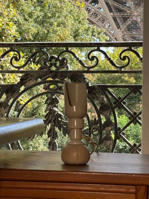 a vase on a table with a view of the eiffel tower in the background