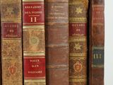 several old books are lined up in a row on a white surface