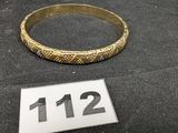 un bracelet en or posé sur une table à côté d'un clavier