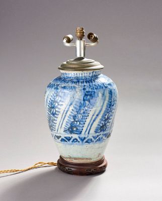 un vase bleu et blanc sur lequel est posée une lampe