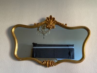 un miroir accroché au mur, avec un lit en arrière-plan