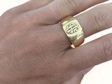 la main d'un homme tenant une bague en or ornée d'une croix