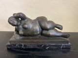 statue d'une femme allongée sur un socle en marbre posé sur une table