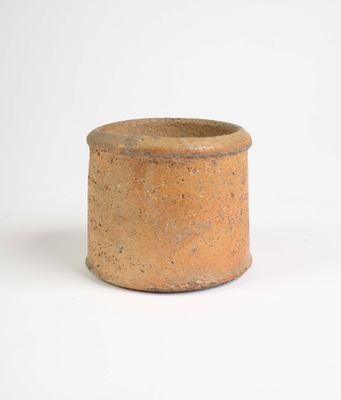 un petit vase brun posé sur une surface blanche