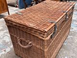 a wicker trunk sitting on the ground in front of a pile of furniture