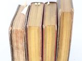 several old books stacked on top of each other on a white surface