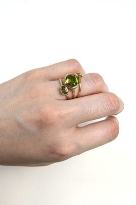 la main d'une femme tenant une bague sertie d'une pierre verte