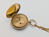 a gold pocket watch with a chain on a white surface