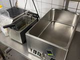 plan de travail en acier inoxydable équipé de deux friteuses dans une cuisine professionnelle