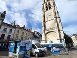 a van parked in front of a church with a clock tower in the background