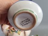 a hand holding a tea pot with a cup on it