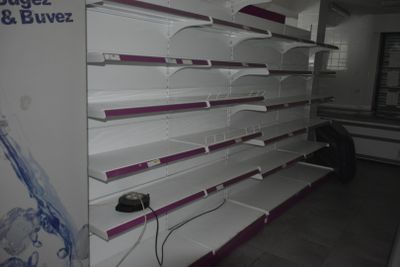 de nombreuses étagères vides dans un magasin, sur lesquelles repose une souris d'ordinateur