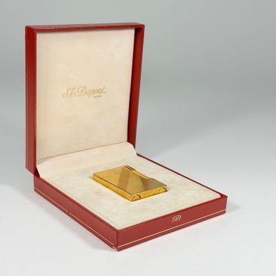une photo d'un briquet plaqué or dans une boîte rouge