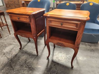 une paire de tables de chevet anciennes avec des tiroirs et une chaise à l'arrière-plan