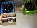 bottles of soda are in crates on the floor next to a microwave