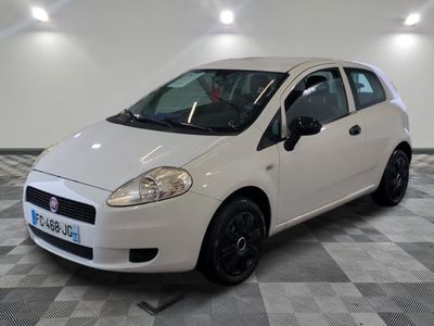 la petite voiture blanche est garée sur un sol en damier