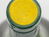 close up of a green bottle with a yellow lid on a plate