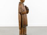 an old wooden statue of a man holding a bird in his hand