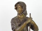 bronze statue of a woman with a stick in her hand