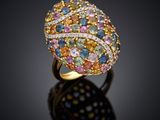 un gros plan d'une bague ornée de pierres multicolores sur un fond noir