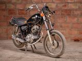 a black motorcycle parked in front of a brick wall
