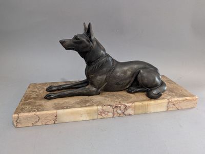 statue d'un chien couché sur un socle en marbre, sur fond gris