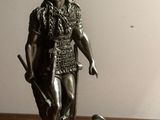 une statue représentant un homme muni d'une épée et portant un chapeau, posée sur une table