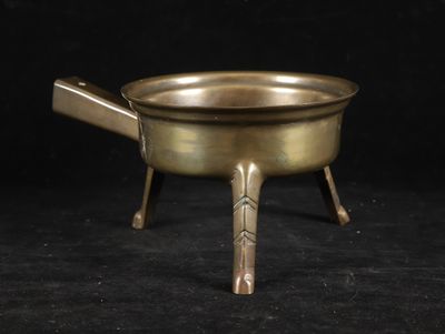 an old brass pot with a wooden handle on a black background