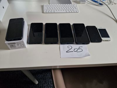 Plusieurs téléphones portables sont alignés sur une table, à côté d'un clavier et d'une souris
