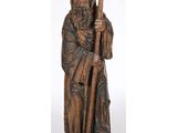 une vieille statue en bois représentant un homme tenant un bâton