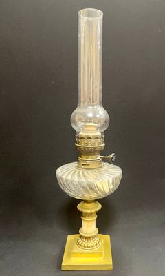 une lampe en verre à l'ancienne avec un pied doré sur fond noir