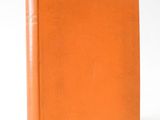 an orange book sitting on top of a white surface