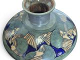 a blue and green vase sitting on top of a white table