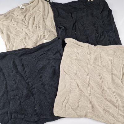 trois coussins tricotés de couleurs différentes posés sur un fond blanc
