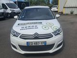 La voiture est garée sur le parking, avec d'autres véhicules en arrière-plan.