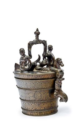 un petit récipient en métal surmonté d'une statuette