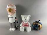 two figurines of a man and a teddy bear next to an apple