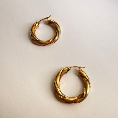 two pairs of gold toned hoop earrings on a white surface