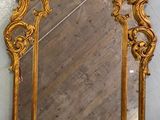 miroir doré et ouvragé accroché au mur d'une pièce au sol en parquet