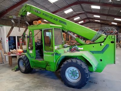 a green crane that is parked inside of a building
