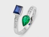un gros plan d'une bague sertie de deux pierres, une émeraude et un saphir