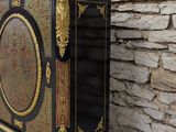 a black and gold cabinet sitting against a stone wall