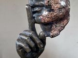 a bronze sculpture of a hand holding a rock