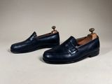 a pair of black leather loafers with a gold toe