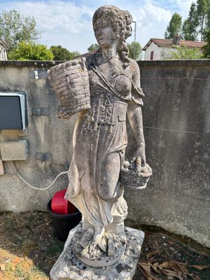 une statue représentant une femme tenant un panier à la main