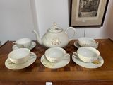 a table with a tea set on it and a picture on the wall in the background