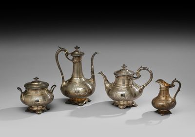 trois théières en argent et une cafetière, posées sur des socles