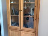 a tall wooden cabinet with glass doors in a room