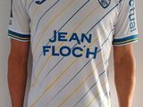 un homme debout, vêtu d'un maillot de foot